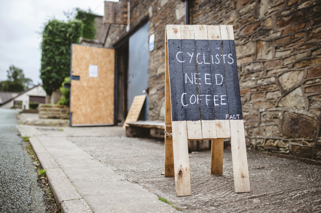 Tabla pred kavarno z napisom »cyclists need coffee«