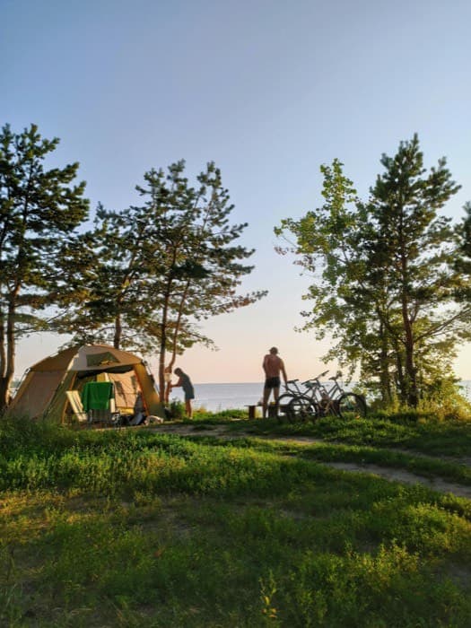Bikepacking camp with a tent by a lake at dusk
